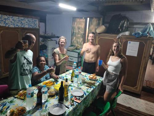 grupa ludzi stojących wokół stołu w obiekcie CHAMBRE CHEZ TAPUHERE LODGE w Fare