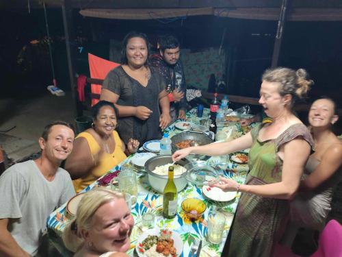 eine Gruppe von Menschen, die um einen Tisch sitzen in der Unterkunft CHAMBRE CHEZ TAPUHERE LODGE in Fare