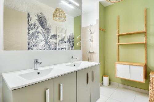 La salle de bains est pourvue d'un lavabo blanc et de murs verts. dans l'établissement Maison pour 4 - jardin - 600m de la plage, à Barbâtre