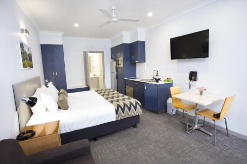 a hotel room with a bed and a table and a kitchen at Altitude Motel Apartments in Toowoomba