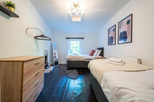 ein Schlafzimmer mit 2 Betten und einer Kommode darin in der Unterkunft Chapel Lodge by Tŷ SA in Newport
