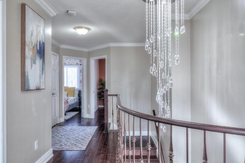 a hallway with a staircase with a chandelier at Premier Villas in Ajax