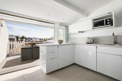 une cuisine avec des placards blancs et une grande fenêtre dans l'établissement Sun Marina Port soleil, au Cap d'Agde
