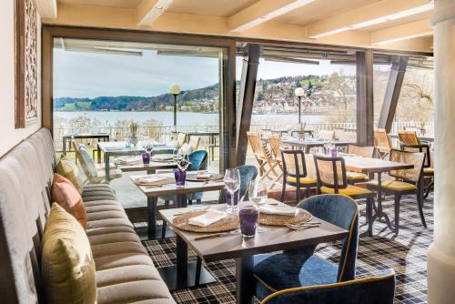 a restaurant with tables and chairs and a large window at Strandhotel Schmerikon in Schmerikon