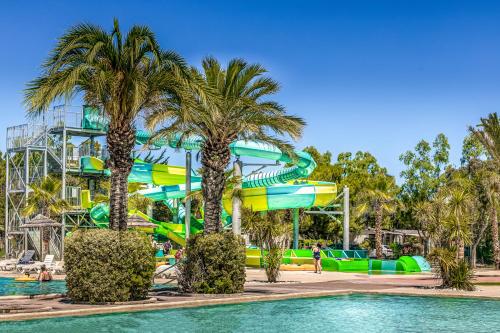 a water slide at a water park with palm trees at Camping L'Oasis et California in Le Barcarès