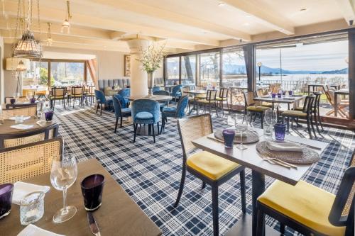 a restaurant with tables and chairs and windows at Strandhotel Schmerikon in Schmerikon