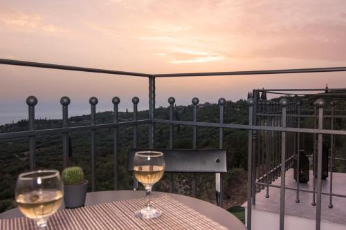 a table with two glasses of wine on a balcony at Lithorama Residence Mani - Second Floor in Koúmani