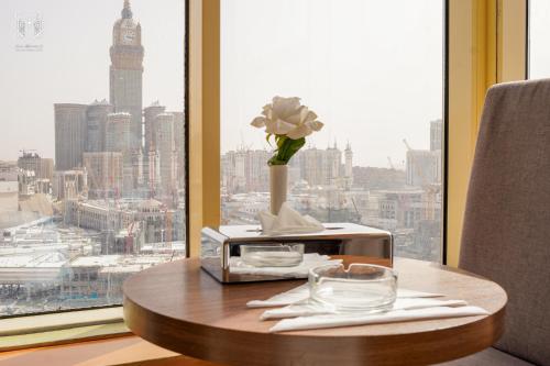 a table with a vase of flowers and a window at Manarat Gaza Hotel - Al Haram Tower in Makkah