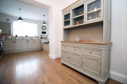 uma cozinha com armários brancos e uma grande ilha em Nessa’s Nook by Tŷ SA - Newport em Newport