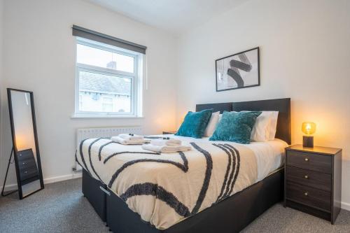um quarto com uma cama com almofadas azuis e uma janela em Clayton Street by Tŷ SA em Newport