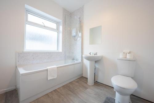 a white bathroom with a toilet and a sink at Clayton Street by Tŷ SA in Newport