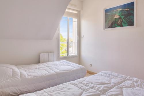 deux lits dans une chambre blanche avec une fenêtre dans l'établissement Proche plages et commerces, appartement pour 4, à Fouesnant