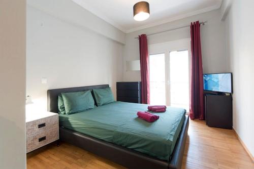 um quarto com uma cama com televisão e almofadas vermelhas em Central apartment 3' to Metaksourgio metro station em Atenas