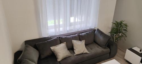 a couch with pillows in a living room with a window at Apartman Stanković in Odžaci