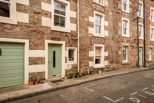 a brick building with green doors on a street at Dove Street Apartment in Cellardyke