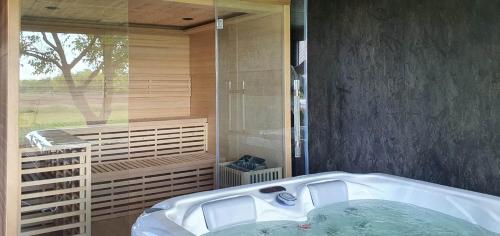 a bath tub in a bathroom with a window at Héthatár Wellness Vendégház - Fecskefészek in Pusztavacs