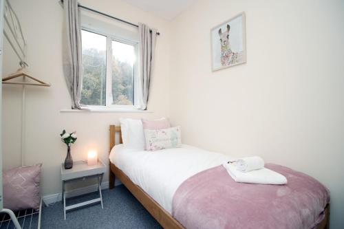 a small bedroom with a bed and a window at Parkview by Tŷ SA - spacious 3 bed in Newport in Newport