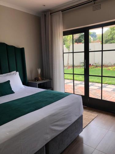 a bedroom with a large bed and a large window at Serene Guesthouse in Middelburg