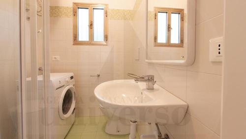 La salle de bains blanche est pourvue d'un lavabo et d'un lave-linge. dans l'établissement Bungalow Dancalia, à Eraclea Mare