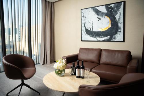 فندق الما ALMA Hotel في الرياض: غرفة معيشة مع أريكة وطاولة مع زجاجات النبيذ