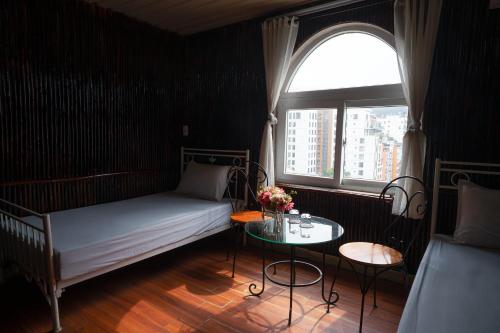 a bedroom with a bed and a table and a window at Chân Mây Tam Đảo in Tam Ðảo