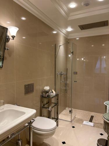 a bathroom with a shower and a toilet and a sink at Hôtel Duc De St-Simon in Paris