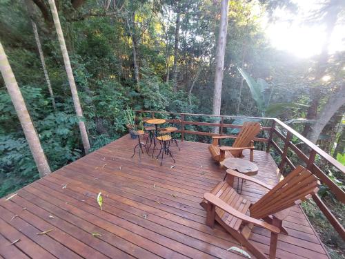 a wooden deck with two chairs and a table at Hospedaria Aikó in São Bento do Sapucaí