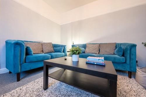 uma sala de estar com dois sofás azuis e uma mesa de centro em Dos Road by Tŷ SA em Newport