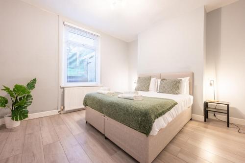 um quarto branco com uma cama e uma janela em Dos Road by Tŷ SA em Newport