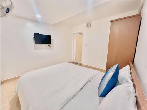 a white bedroom with a bed and a tv at Cosy Hotel & Apartment Dalat in Da Lat