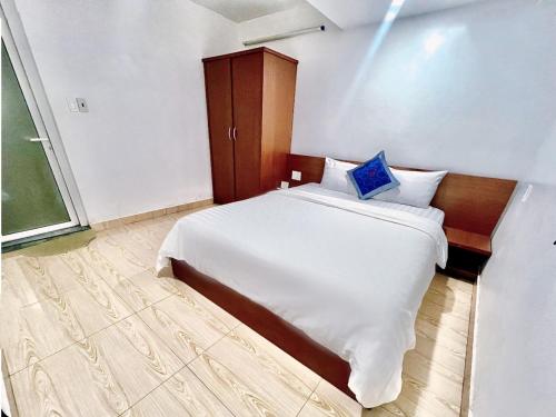a bedroom with a white bed with a blue pillow on it at Cosy Hotel & Apartment Dalat in Da Lat