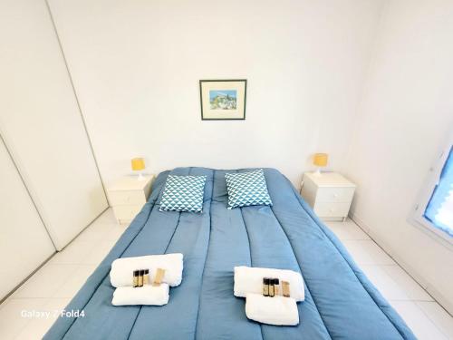 - un lit bleu dans une chambre blanche avec deux oreillers dans l'établissement Quercus YourHostHelper, à Saint-Raphaël