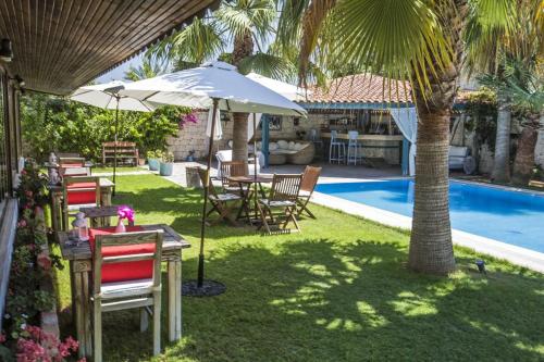 eine Gruppe von Stühlen und Tischen mit Sonnenschirmen neben einem Pool in der Unterkunft Tash Mekan Alaçatı in Alacati