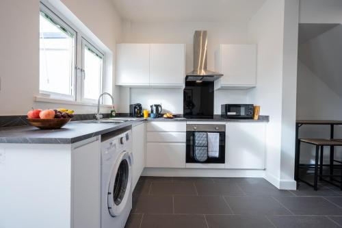 a kitchen with white cabinets and a sink and a dishwasher at Durham View by Tŷ SA in Newport
