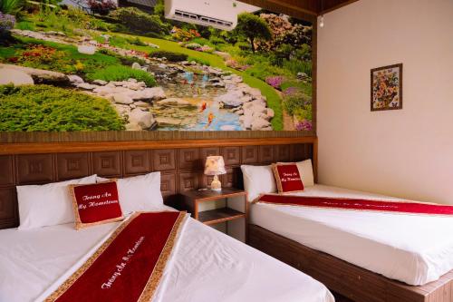 two beds in a room with a painting on the wall at Trang An Hometown Homestay in Ninh Binh