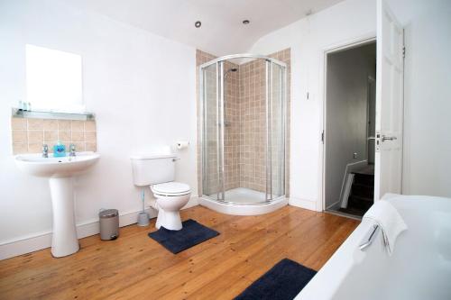 a bathroom with a shower and a toilet and a sink at Evansfield Close by Tŷ SA in Cardiff