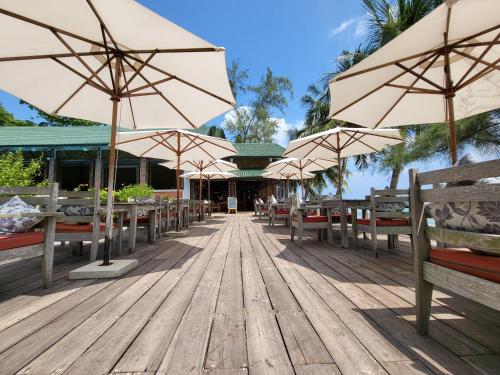 una terraza de madera con sombrillas, mesas y bancos en Ancarine Beach Resort en Phu Quoc