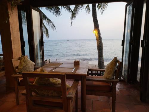 Ancarine Beach Resort في فو كووك: طاولة وكراسي مطلة على المحيط
