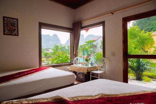 a bedroom with two beds and a large window at Trang An Hometown Homestay in Ninh Binh