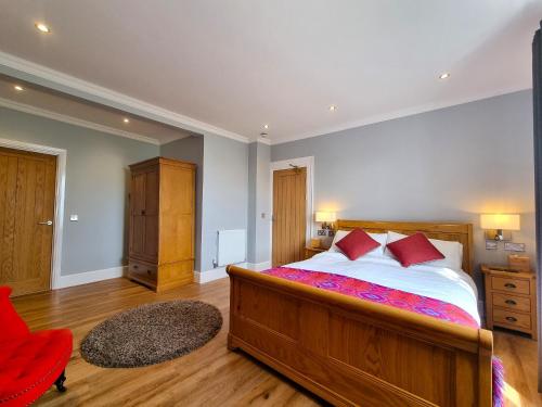 a bedroom with a large bed and a red chair at Min y Don Llandudno in Llandudno