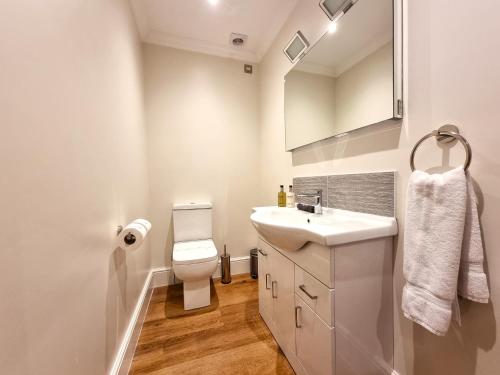 uma casa de banho branca com um lavatório e um WC em Min y Don Llandudno em Llandudno