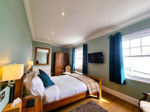 a bedroom with a large bed with blue curtains at Min y Don Llandudno in Llandudno