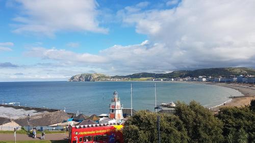 a view of a beach with a lighthouse and the ocean at Min y Don Llandudno in Llandudno
