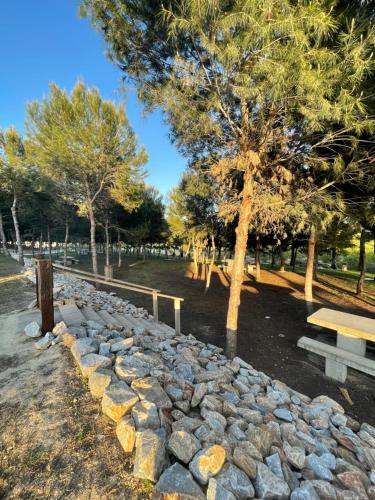 a park with a stone wall and a bench and trees at Casa Amarela Guesthouse, Algorfa in Algorfa