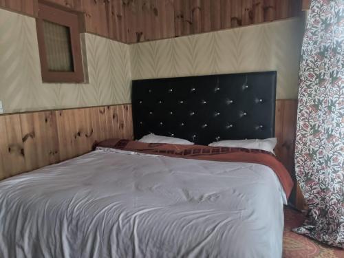 Hotel Blue water في Anantnāg: غرفة نوم مع سرير كبير مع اللوح الأمامي الأسود