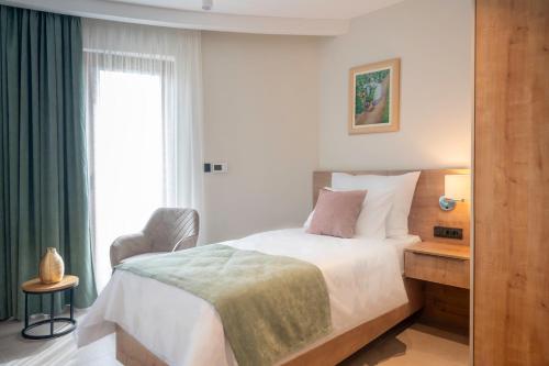 a bedroom with a bed and a chair and a window at Dve Kule Resort & Winery in Bačinci