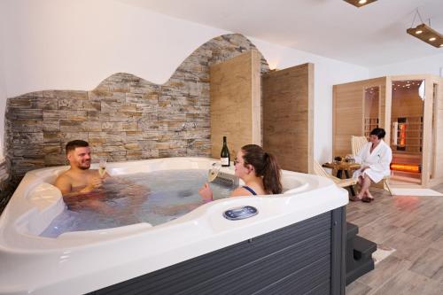 un homme et une femme dans un bain à remous dans l'établissement Cottage Osojnik - Alpine escape with Wellness, à Solčava