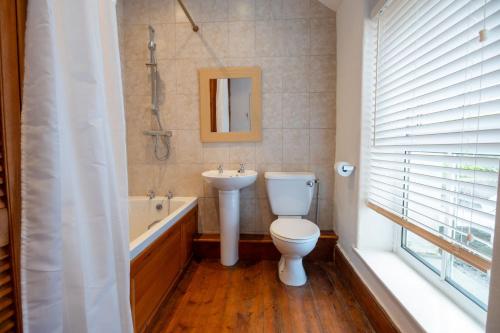 a bathroom with a toilet and a sink and a tub at 24 Rosemary Lane in Beaumaris