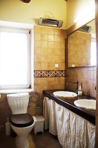a bathroom with two sinks and a toilet and a mirror at Hillside Villa over Lemonodasos in Galatas