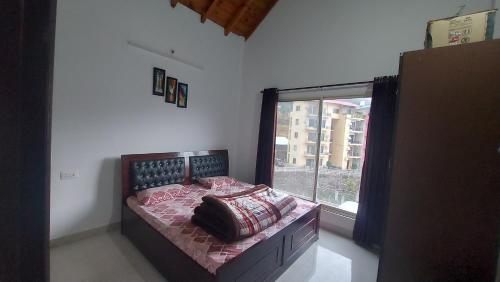 a bedroom with a bed with a large window at BNB Room in Nainital